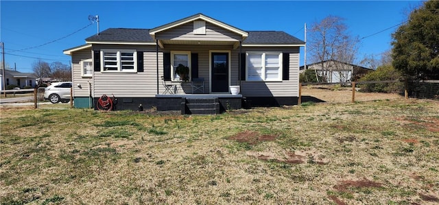 bungalow featuring covered porch, a front lawn, and fence