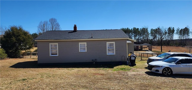 view of side of home featuring a shingled roof, a lawn, and a chimney