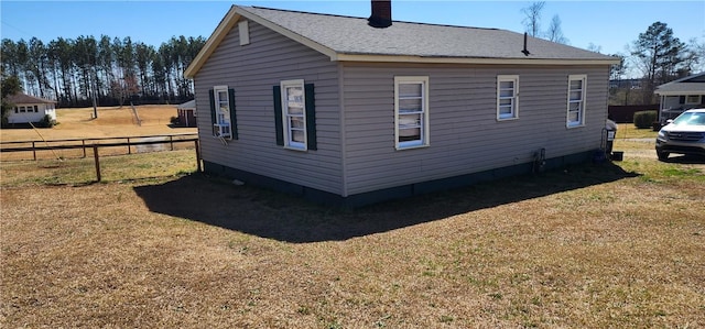 view of side of property featuring a lawn, a chimney, and fence