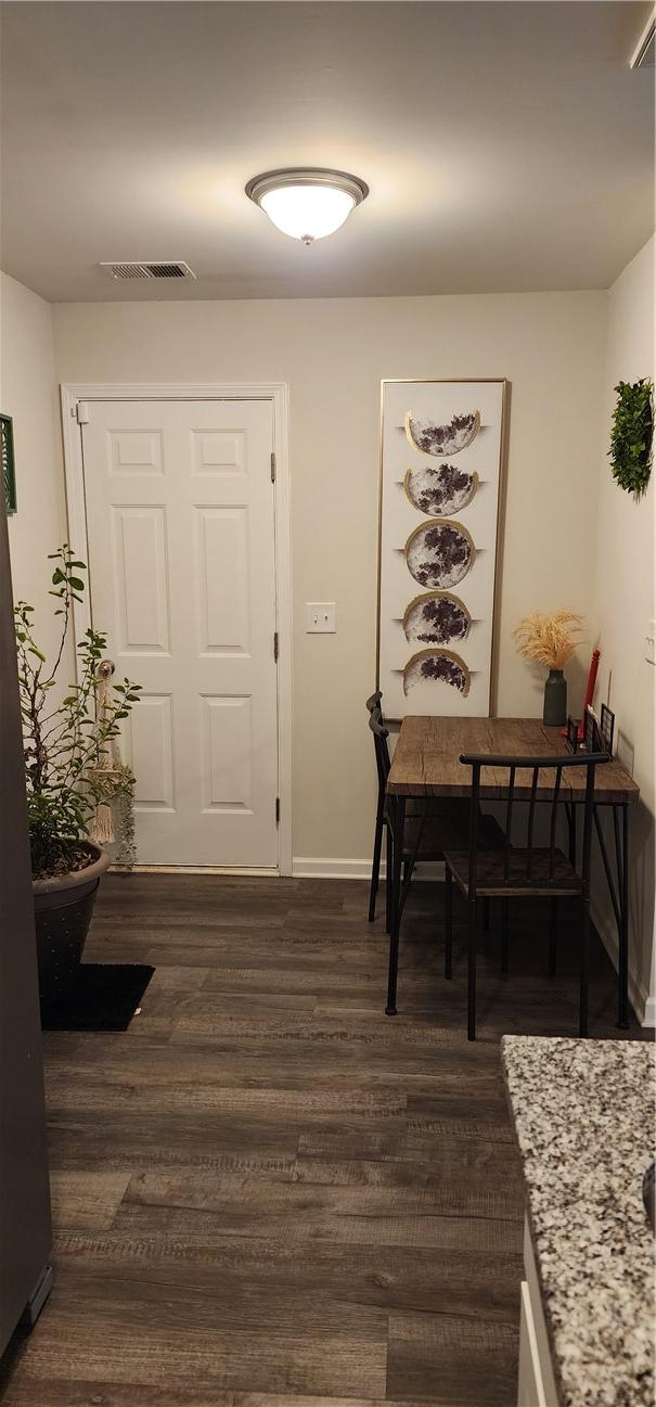 dining area featuring dark wood-style floors, visible vents, and baseboards