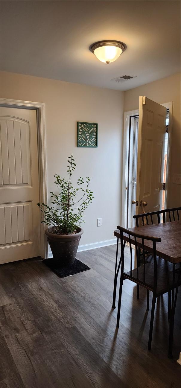 dining area with dark wood-type flooring, baseboards, and visible vents