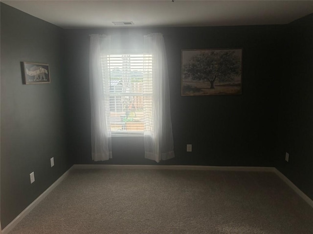 spare room featuring carpet flooring, visible vents, and baseboards