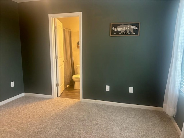 unfurnished bedroom featuring connected bathroom, baseboards, and carpet