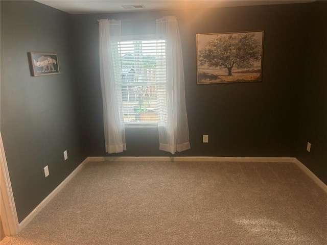 empty room with carpet flooring, baseboards, and visible vents