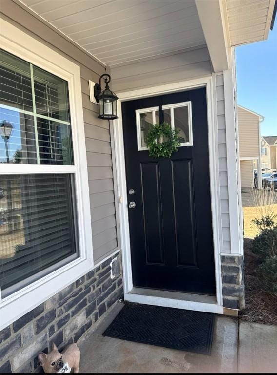 entrance to property featuring stone siding and a porch