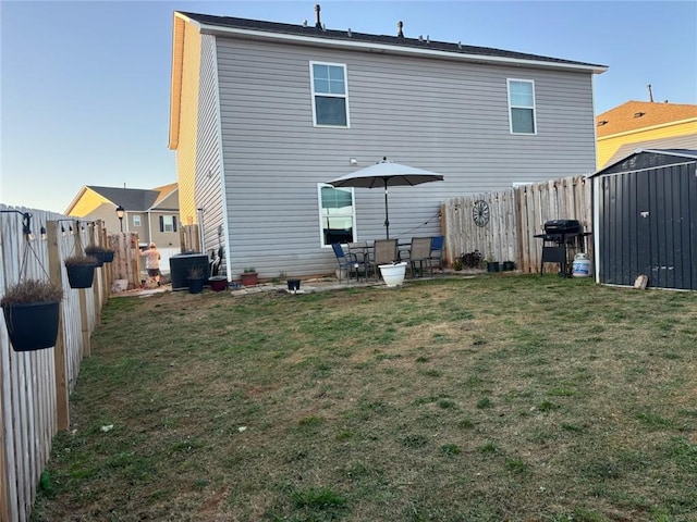 rear view of house with an outbuilding, a lawn, a fenced backyard, and a shed