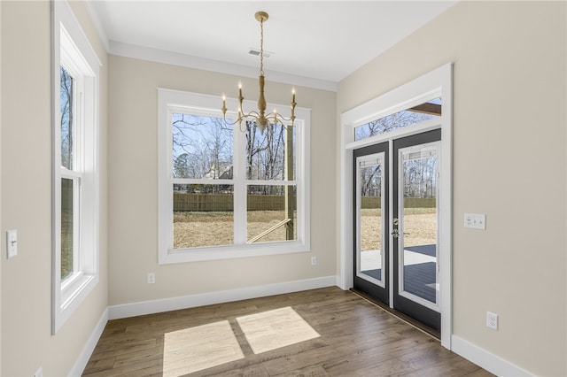 doorway with a chandelier, visible vents, baseboards, and wood finished floors