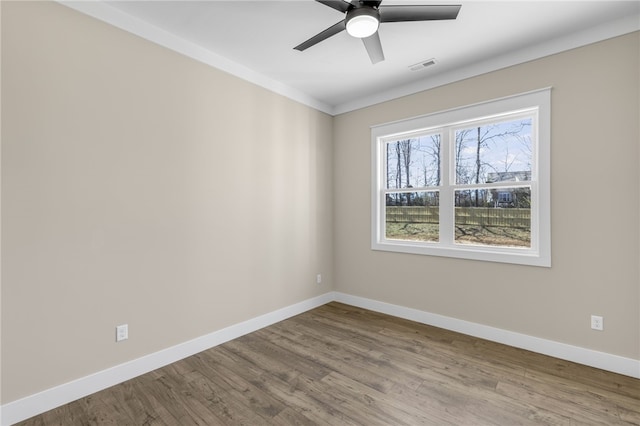 spare room with visible vents, a ceiling fan, baseboards, and wood finished floors