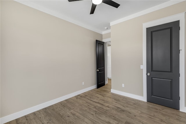 unfurnished bedroom featuring a ceiling fan, crown molding, wood finished floors, and baseboards