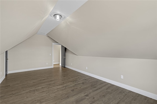 bonus room featuring dark wood-style floors, baseboards, and vaulted ceiling