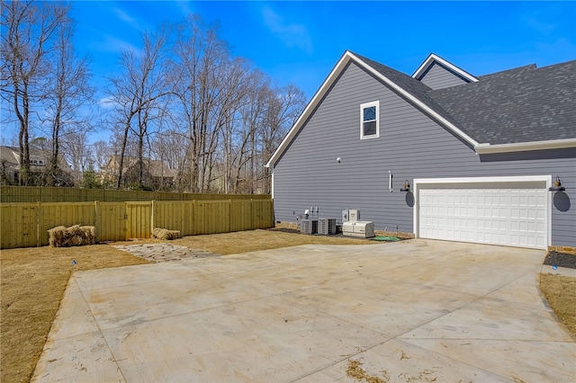 view of property exterior with a shingled roof, concrete driveway, and fence