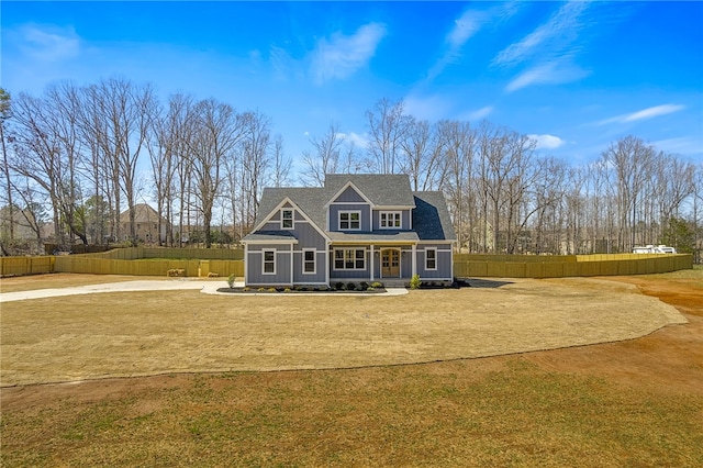 shingle-style home featuring roof with shingles, a front yard, and fence