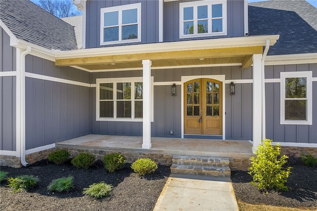 entrance to property featuring covered porch, board and batten siding, and roof with shingles