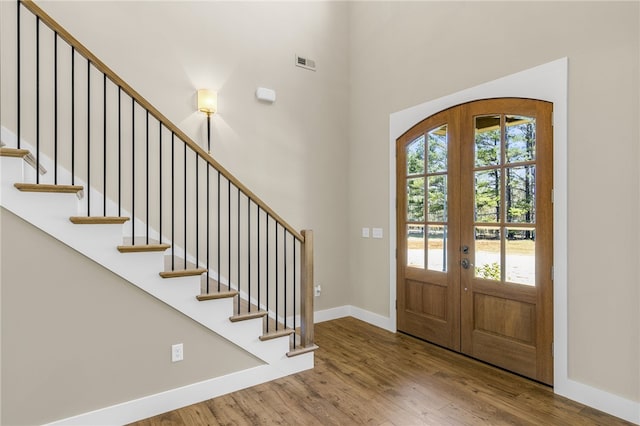 entrance foyer with visible vents, baseboards, stairs, french doors, and wood finished floors