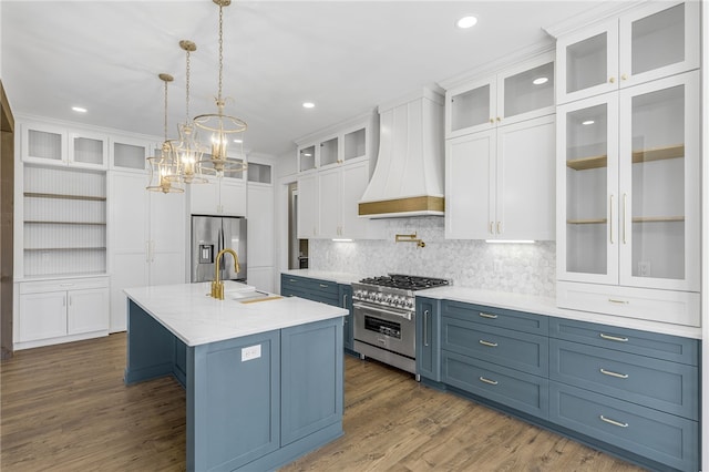 kitchen with premium range hood, white cabinetry, appliances with stainless steel finishes, and a sink