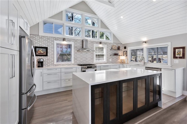 kitchen featuring a sink, stainless steel appliances, light countertops, white cabinetry, and wall chimney range hood