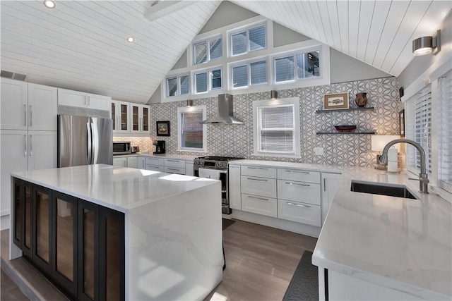 kitchen featuring visible vents, white cabinets, stainless steel appliances, wall chimney exhaust hood, and a sink