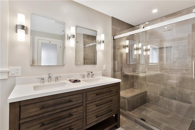 full bath with double vanity, a shower stall, and a sink