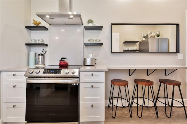 kitchen with open shelves, stainless steel appliances, white cabinets, and wall chimney range hood