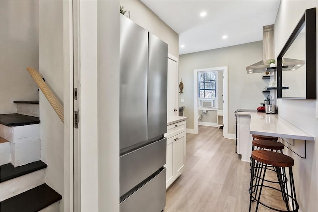 kitchen with open shelves, white cabinetry, freestanding refrigerator, light wood-style floors, and light countertops