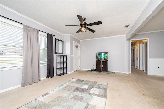 unfurnished living room featuring ceiling fan, carpet, and ornamental molding