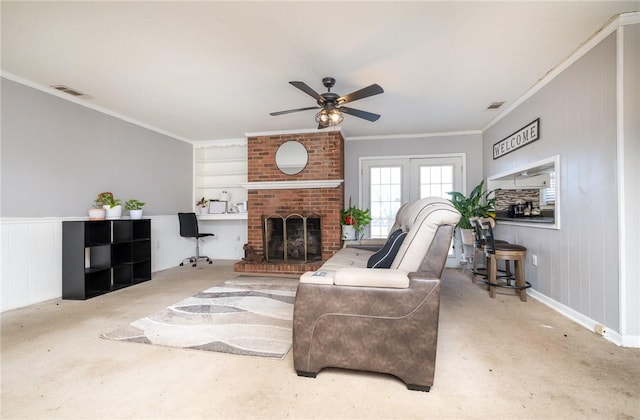 living area with crown molding, a fireplace, visible vents, and ceiling fan