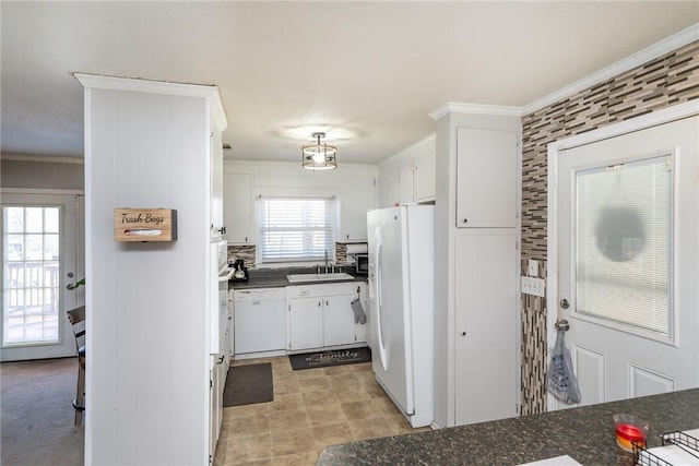 kitchen featuring a sink, dark countertops, white cabinetry, white appliances, and crown molding