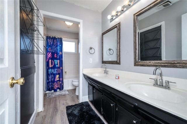 bathroom featuring visible vents, toilet, wood finished floors, and a sink