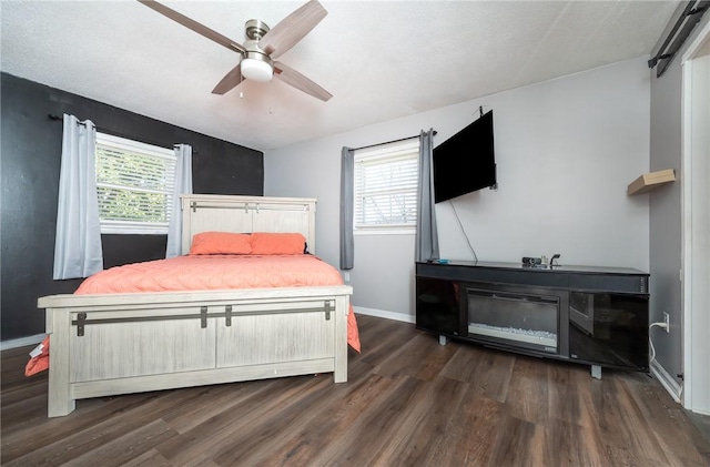 bedroom featuring dark wood finished floors, multiple windows, a ceiling fan, and baseboards