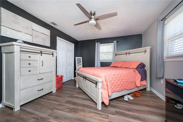 bedroom featuring visible vents, baseboards, dark wood-style floors, and a ceiling fan