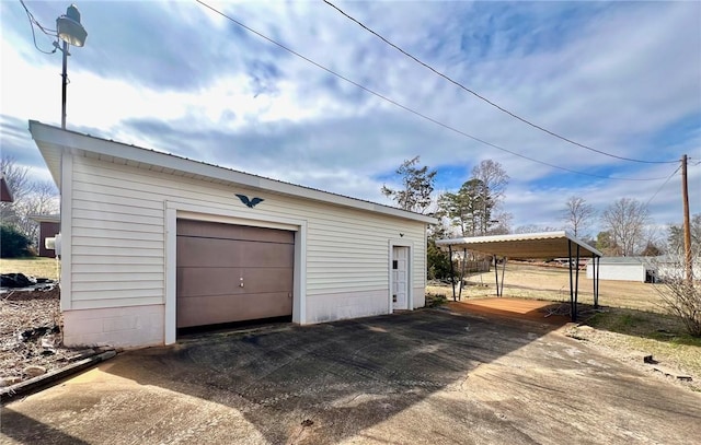 detached garage with a detached carport and driveway