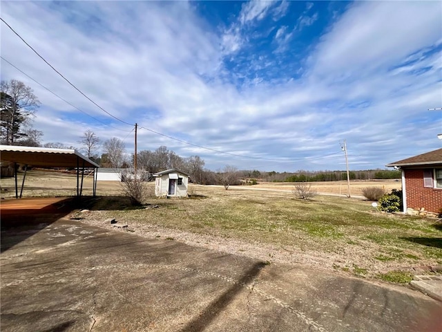 view of yard featuring an outdoor structure, a carport, and dirt driveway