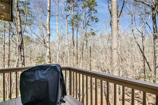 wooden terrace featuring area for grilling and a forest view