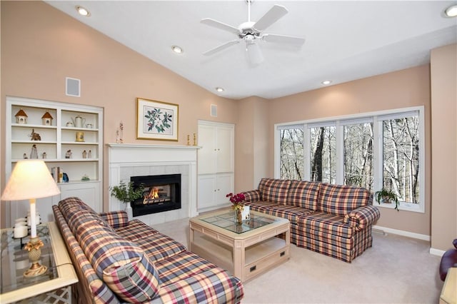 living room featuring baseboards, carpet floors, ceiling fan, vaulted ceiling, and a tiled fireplace