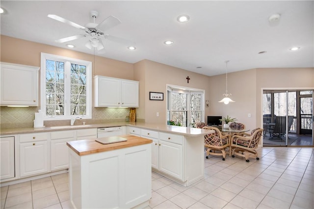 kitchen with a ceiling fan, wooden counters, a kitchen island, a peninsula, and a sink