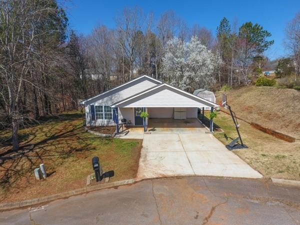 view of front facade with a carport, concrete driveway, and a front yard