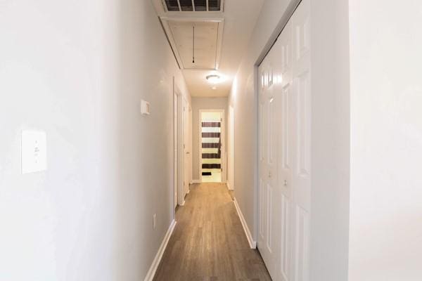 hall with light wood finished floors, visible vents, attic access, and baseboards