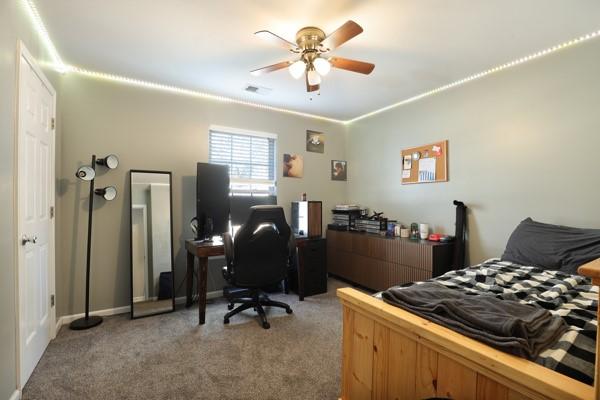 bedroom featuring light carpet, visible vents, and a ceiling fan