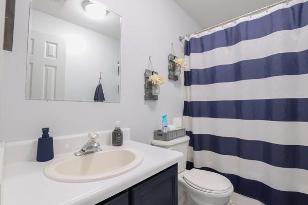 full bath with vanity, a shower with shower curtain, and toilet