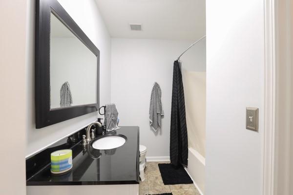 full bath featuring vanity, shower / bathtub combination with curtain, baseboards, visible vents, and toilet