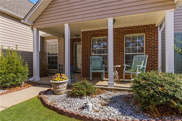 doorway to property with a porch and brick siding