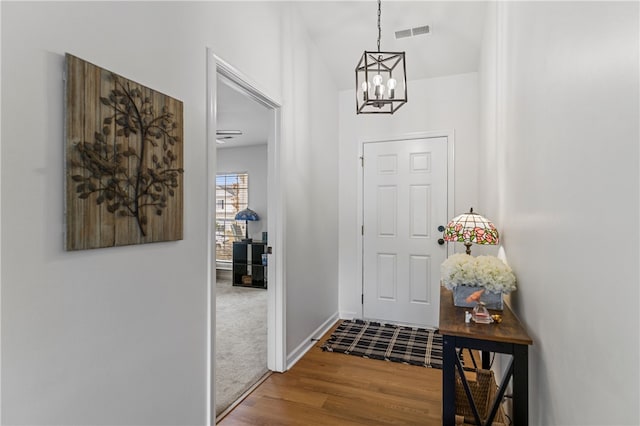 entryway with baseboards, wood finished floors, visible vents, and a chandelier