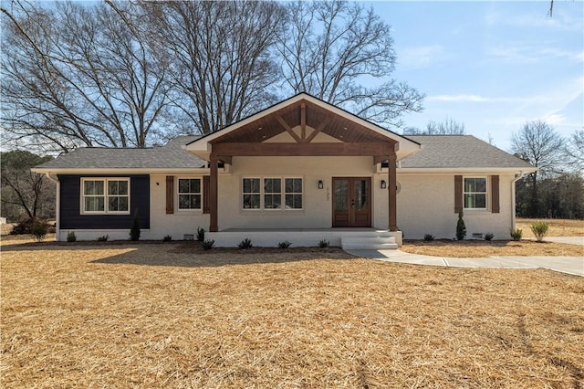 ranch-style home with a front yard, french doors, and roof with shingles