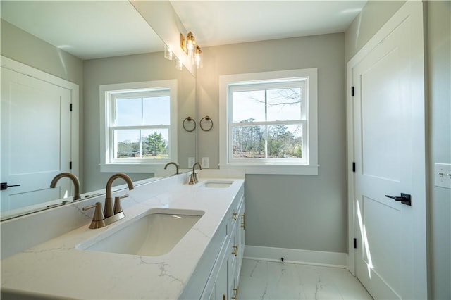 bathroom with plenty of natural light, baseboards, marble finish flooring, and double vanity