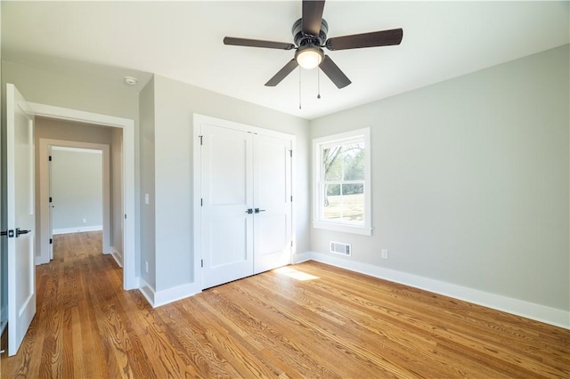 unfurnished bedroom with light wood-style flooring, baseboards, visible vents, and a closet