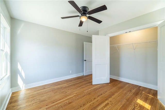 unfurnished bedroom featuring multiple windows, light wood-type flooring, and baseboards