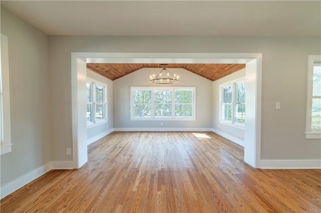 spare room featuring vaulted ceiling, baseboards, an inviting chandelier, and wood finished floors