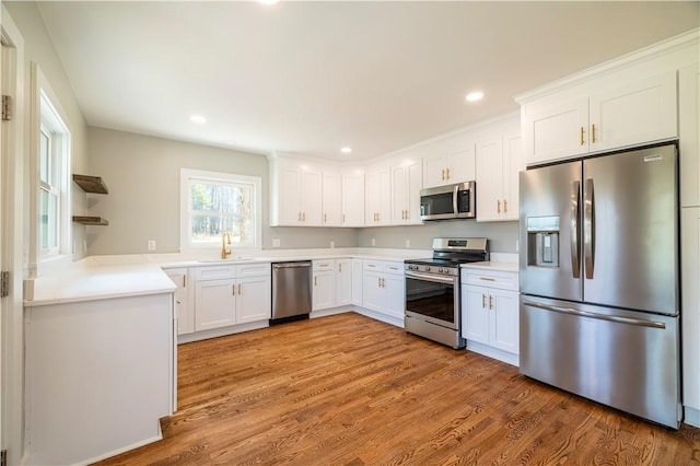 kitchen featuring light wood finished floors, open shelves, a sink, white cabinets, and appliances with stainless steel finishes