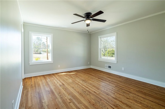 empty room with a ceiling fan, wood finished floors, visible vents, baseboards, and crown molding