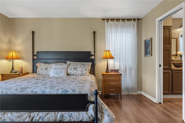 bedroom with a sink, baseboards, and wood finished floors